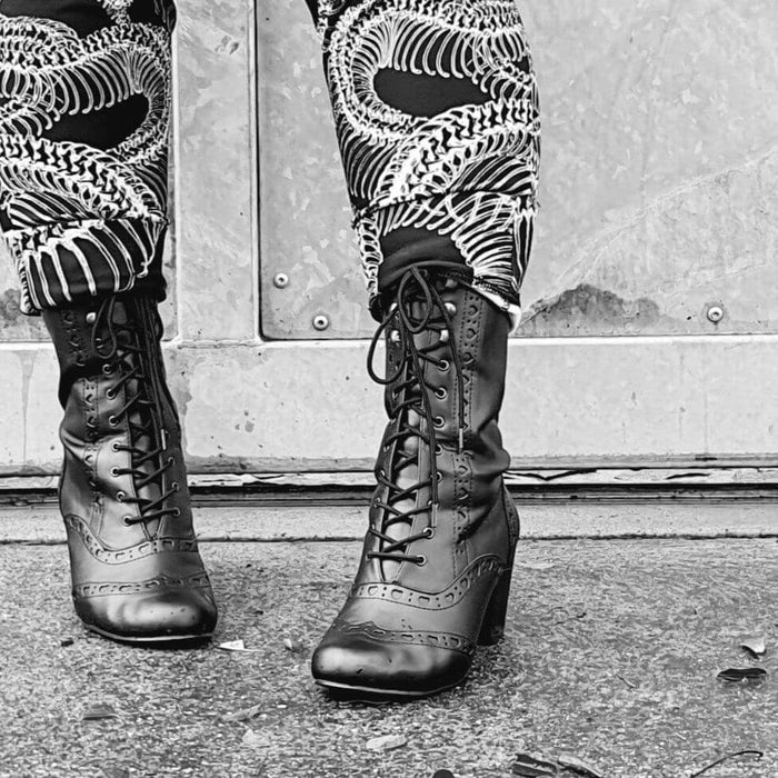 Vivika 200 stylish black lace-up shoes paired with unique patterned pants, perfect for festivals and pole dance.