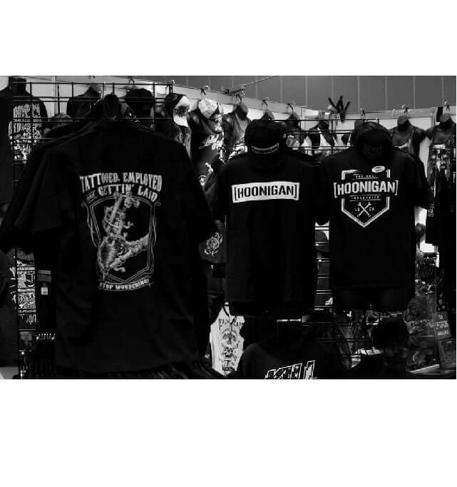 T-shirts featuring tattoo and hoonigan designs at The Melbourne Tattoo Expo booth.