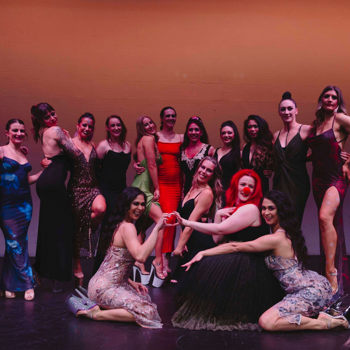 Participants of Miss Pole Dance New Zealand 2024 posing together on stage in elegant outfits.