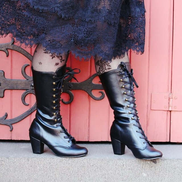 V is for Vivika stylish black lace-up boots paired with a vintage lace dress, perfect for alternative fashion lovers.